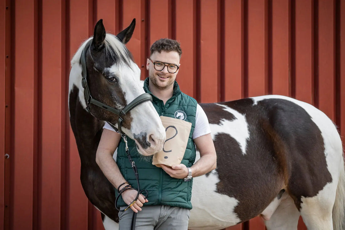 Gründer Ralf Stüber zeigt mit Scheckwallach die Amino Horse Überraschungstüte, stehend für Amino Horse Produktneuheiten, exklusive Angebote & Neuheiten rund um die Marken Amino Horse.